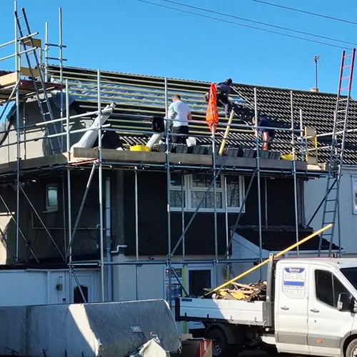 A white truck parked in front of a house under construction.