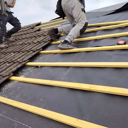 A couple of men standing on top of a roof.