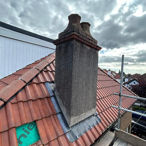 A red tiled roof with a chimney on top of it.